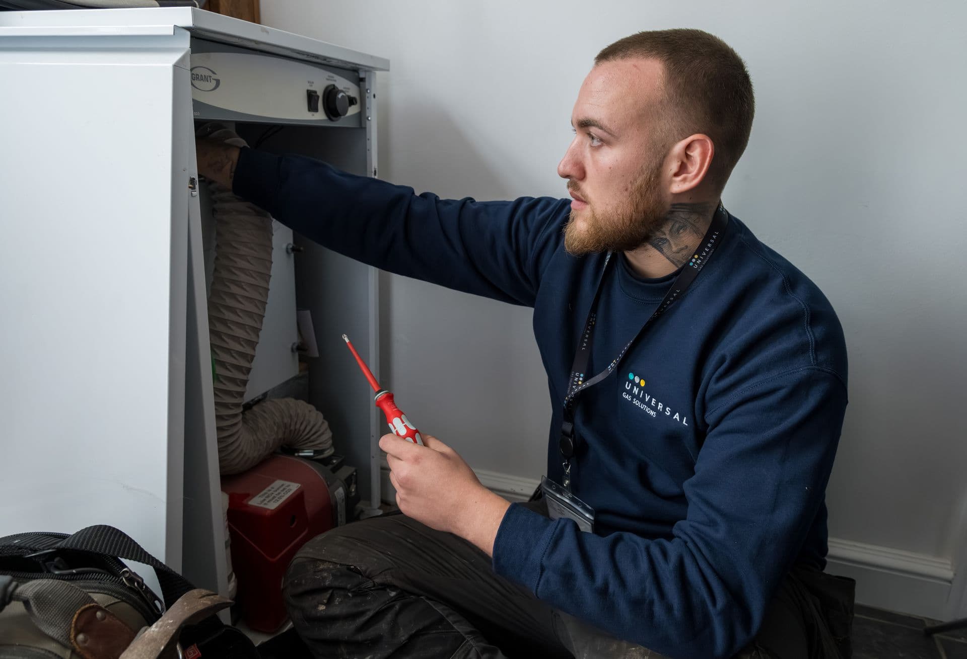 An engineer checking a boiler with a screwdriver