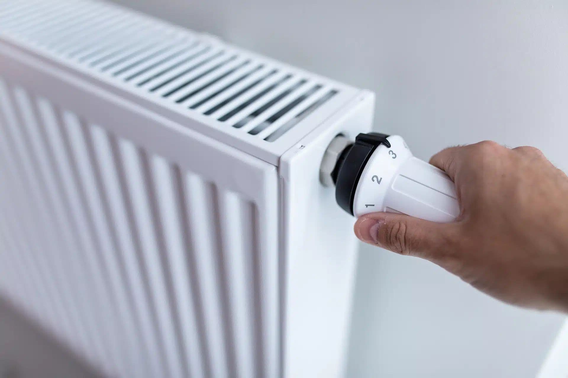A hand turning a radiator valve to adjust the heat